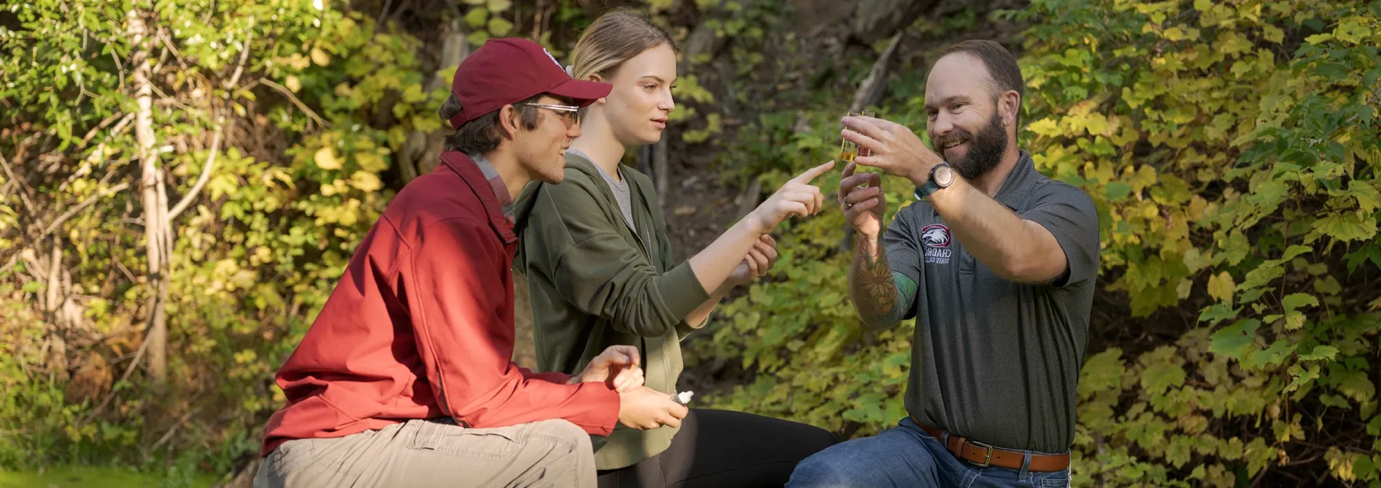 A rangeland professor and two students examing a water sample during a field trip